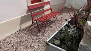 A red bench outside a building with a window. - Welcome to the The Old Manse, Horton, newly refurbished, meticulously designed. (Swansea)
