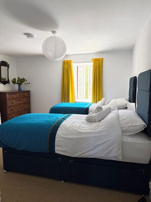 A bedroom with a bed, two bedside tables, a dresser, a window with curtains, and a hanging light fixture. - The Old Manse, newly refurbished, 4 bedrooms, woodburner, 5 mins from the beach (Swansea)