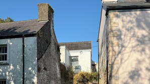 A narrow street with stone walls and a paved path leading to a white building with a visible window. - Welcome to the The Old Manse, Horton, newly refurbished, meticulously designed. (Swansea)