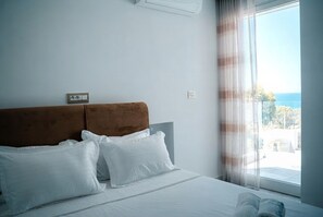 A hotel room with a bed, a headboard, a window with curtains, and a view of the outdoors. - Sandra 14 (Marsa)