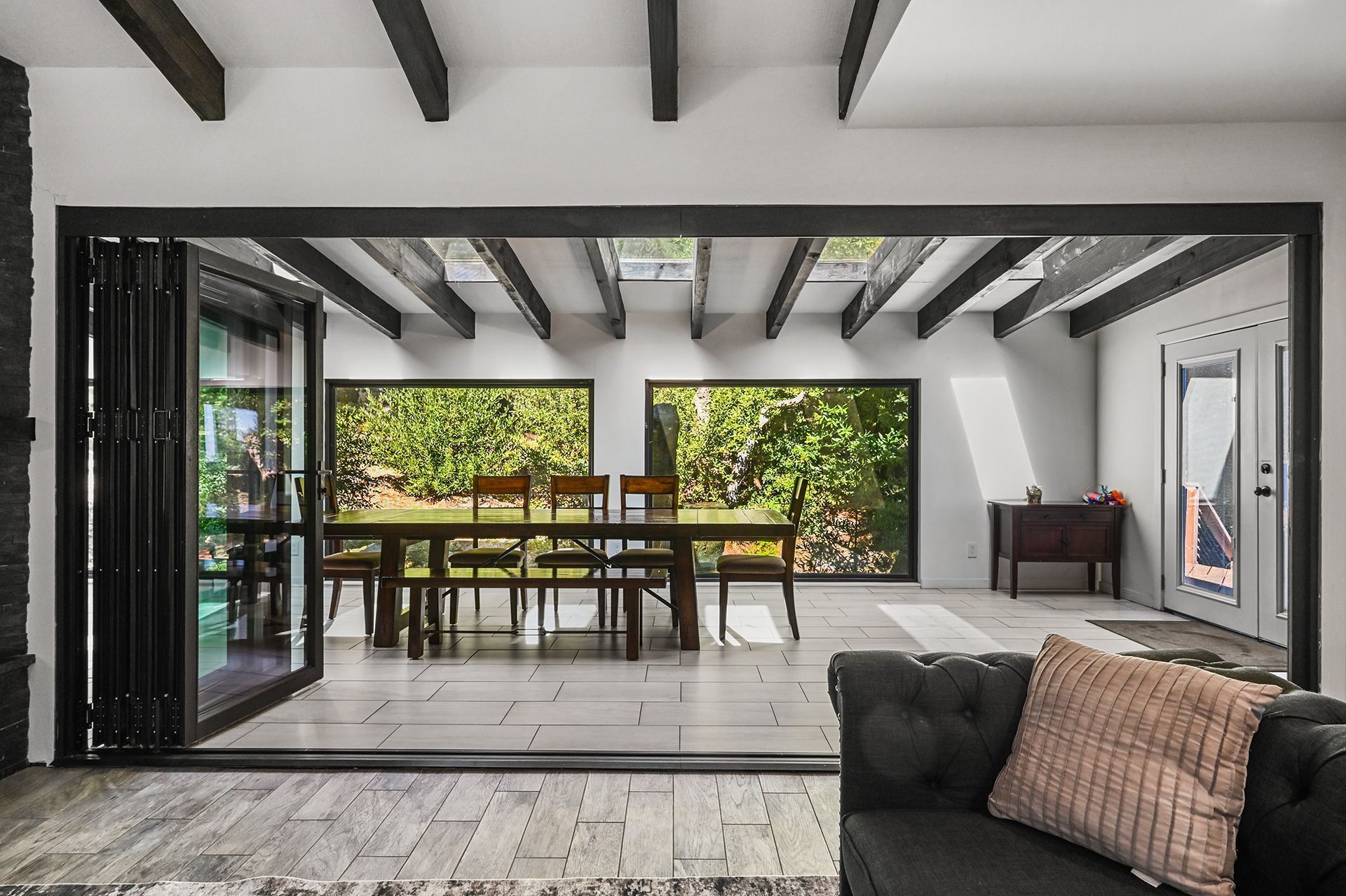 An interior space with a dining area, a sofa, and a view of the outdoors.