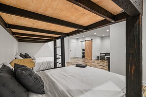 A bedroom with two beds, a wooden ceiling, and a sliding door leading to a bathroom. - Calistoga Retreat | Family Friendly + Private Pool (Calistoga)