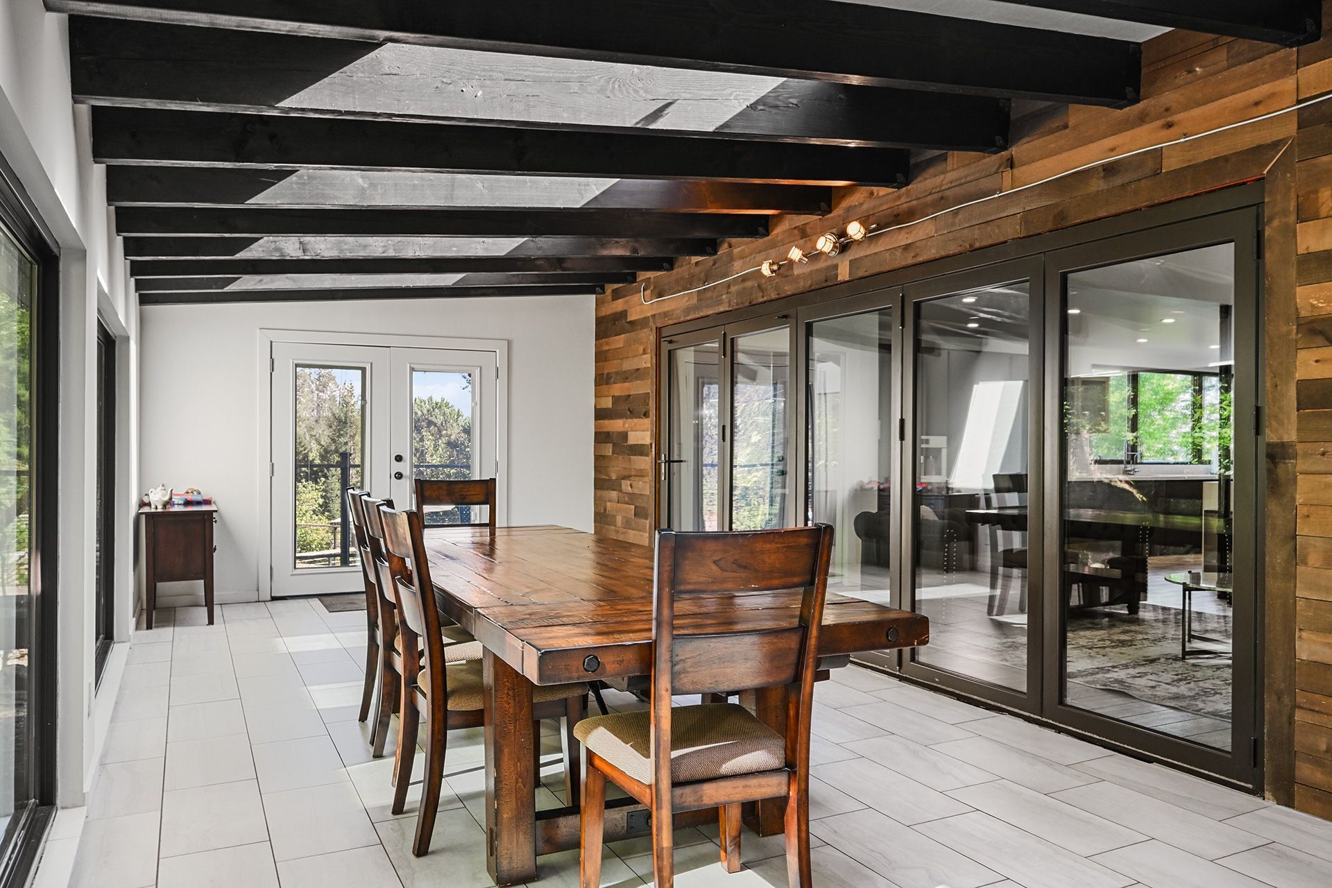 A dining area with a wooden table and chairs, a sliding glass door leading to a balcony, and a view of the outdoors.