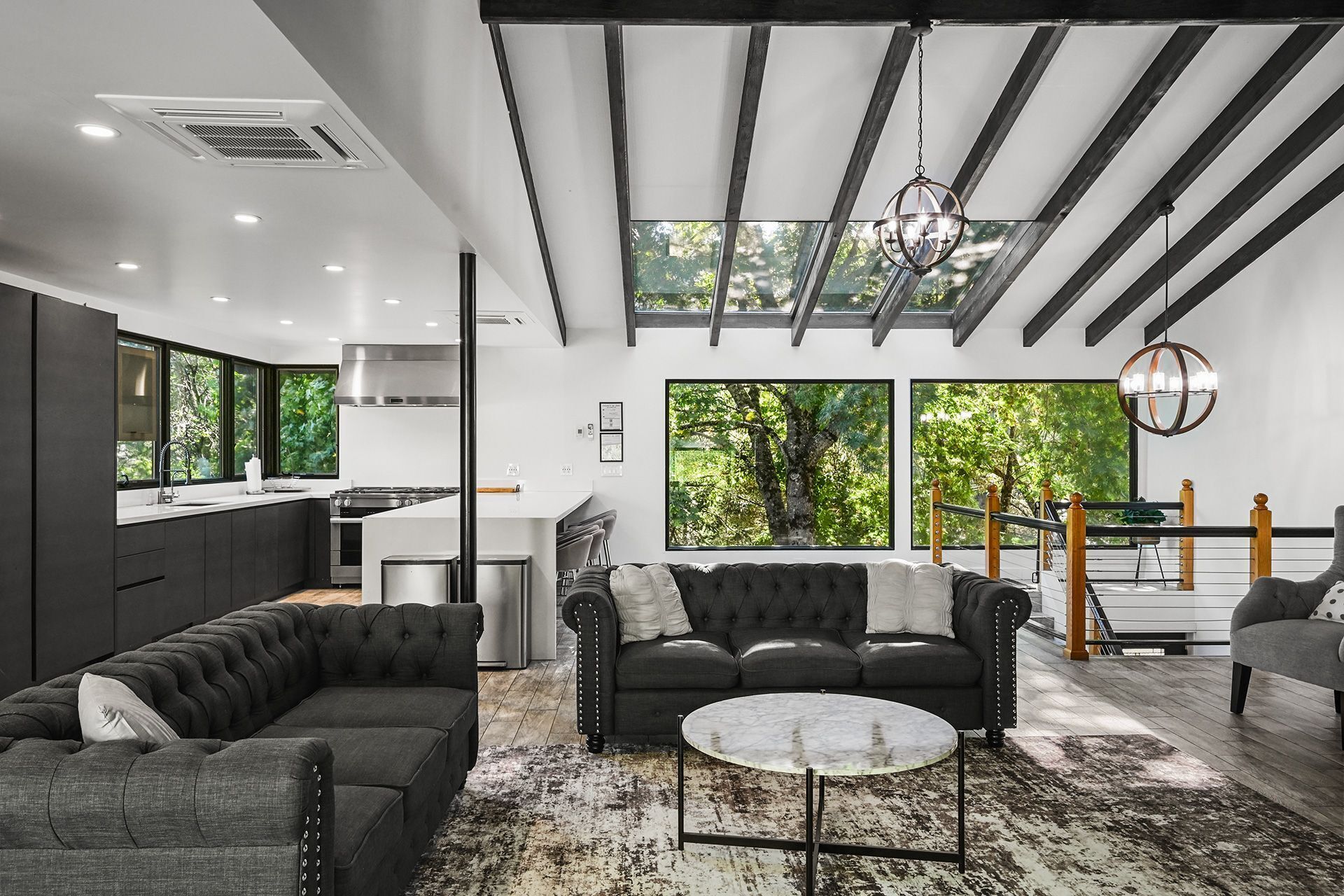 A modern living space with a kitchen, seating area, and large windows.