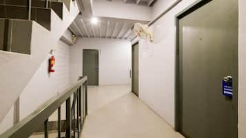 A hallway with a staircase, a door, and a fire extinguisher.