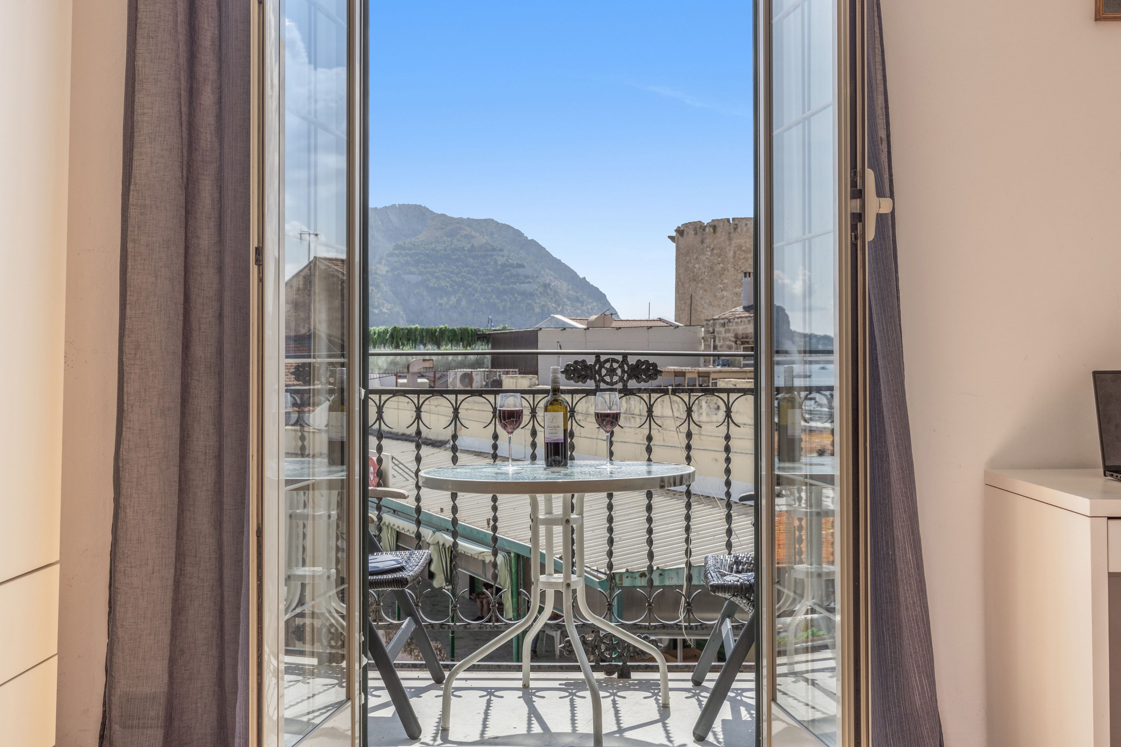 Ein Balkon mit Tisch, Stühlen und einer Weinflasche.