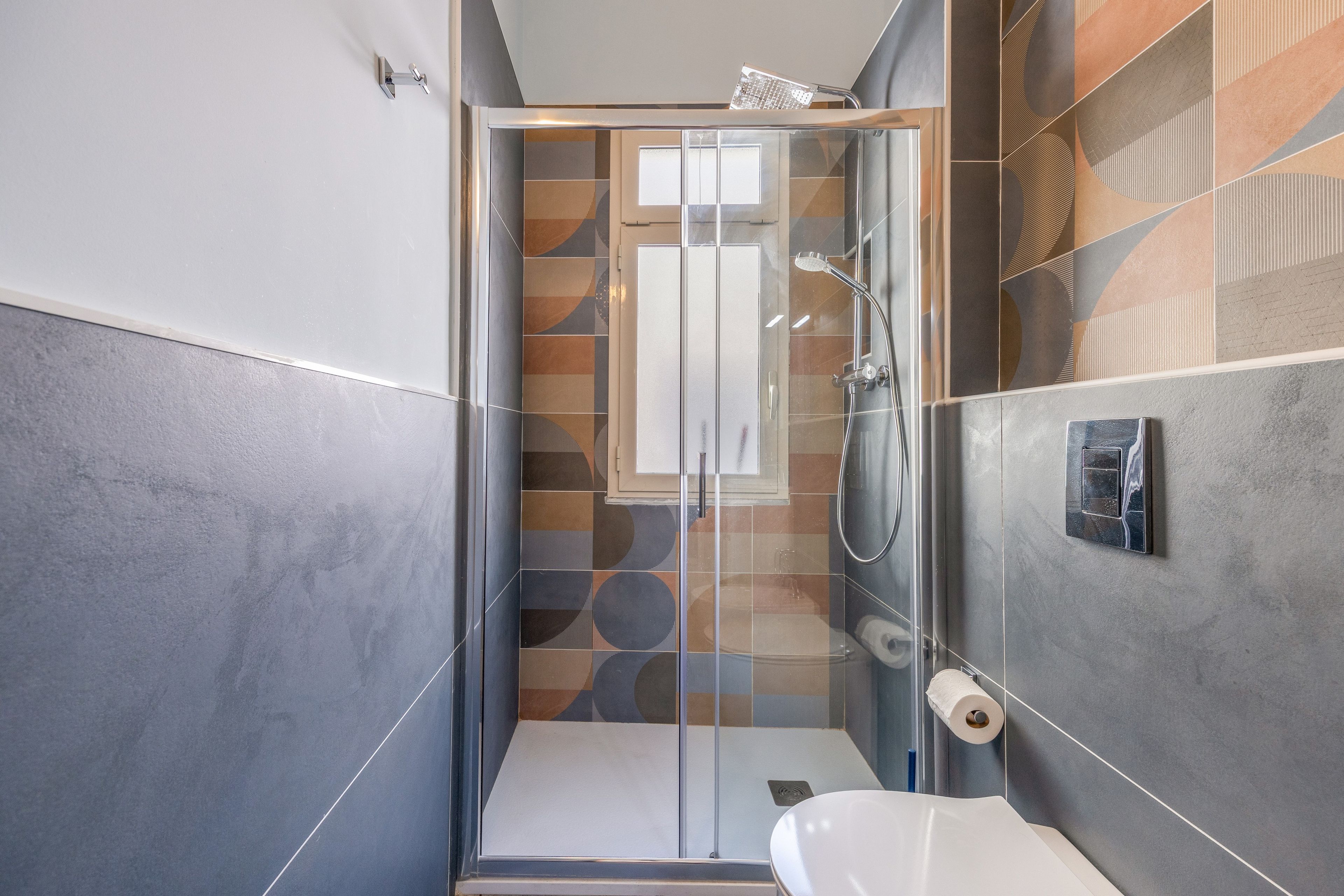 A modern bathroom with a glass-enclosed shower, a toilet, and a sink.
