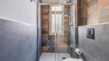 A modern bathroom with a glass-enclosed shower, a toilet, and a sink.