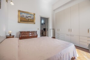 A bedroom with a large bed, a wooden dresser, a painting on the wall, and a wardrobe. - Mondello Holidays - Casa Goethe Apartment with Sea View, WiFi, and Air Conditioning (Palermo)