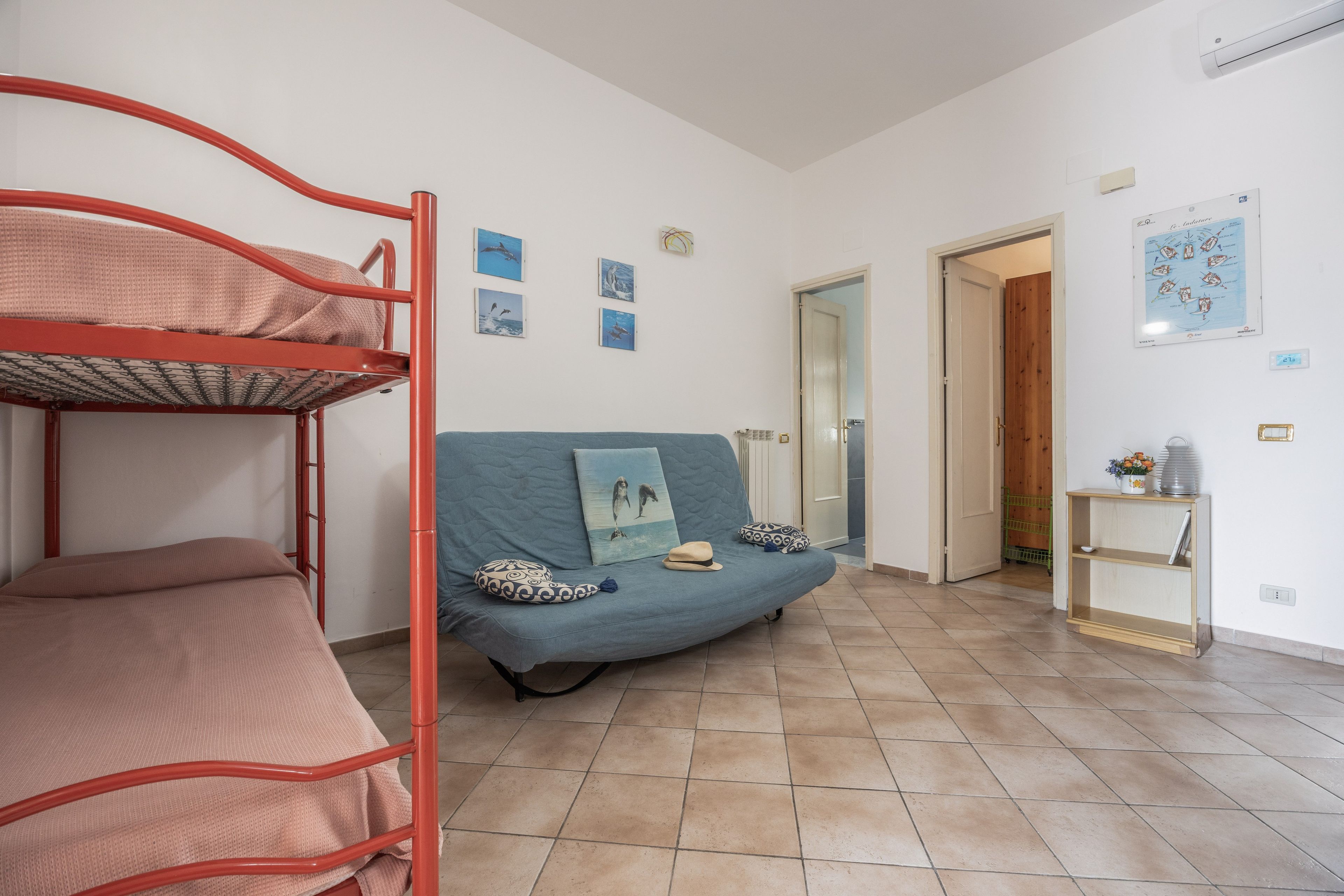 A room with bunk beds, a sofa, and a small table with a plant.