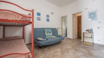A room with bunk beds, a sofa, and a small table with a plant.