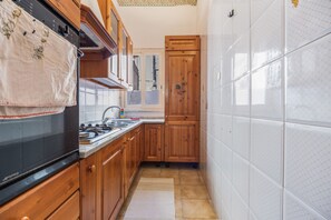 A kitchen with wooden cabinets, a stove, and a tiled backsplash. - Mondello Holidays - Casa Goethe Apartment with Sea View, WiFi, and Air Conditioning (Palermo)