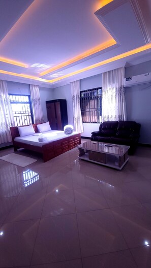 A modern bedroom with a bed, a sofa, and a glass coffee table.