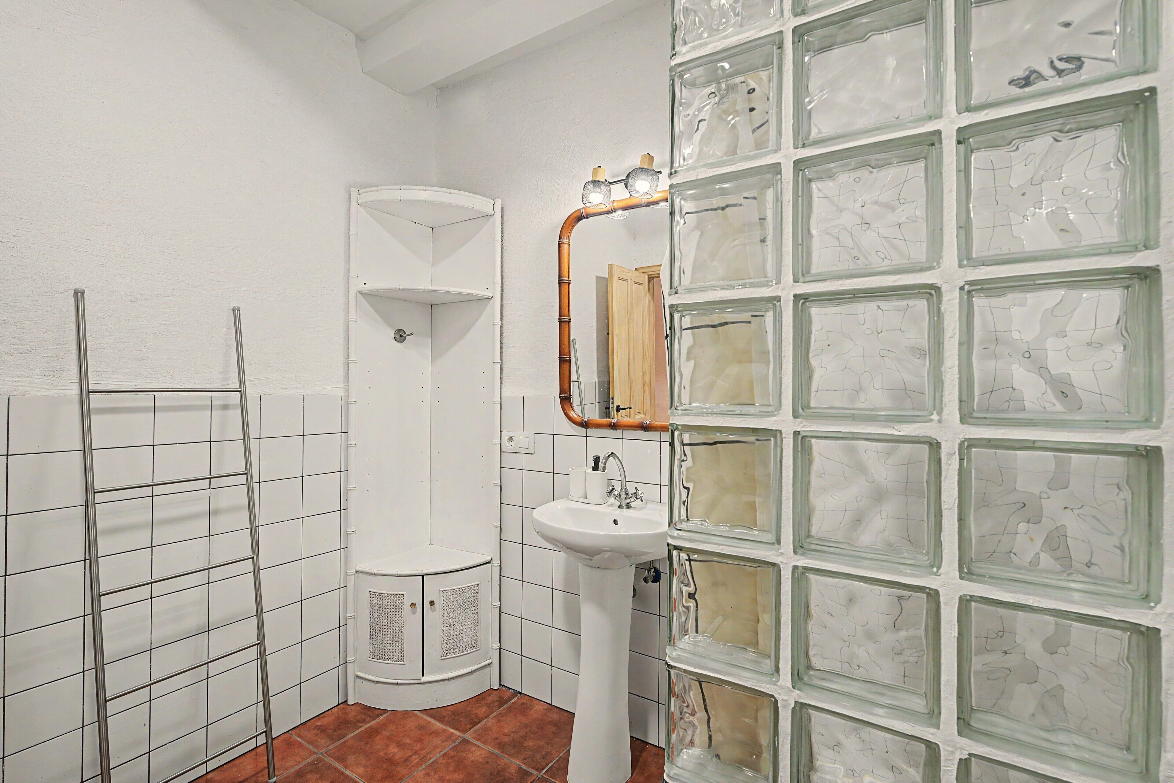 A bathroom with a white sink, a mirror, and a shower enclosure.