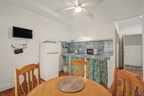 A compact kitchen with a ceiling fan, a microwave, and a small refrigerator.