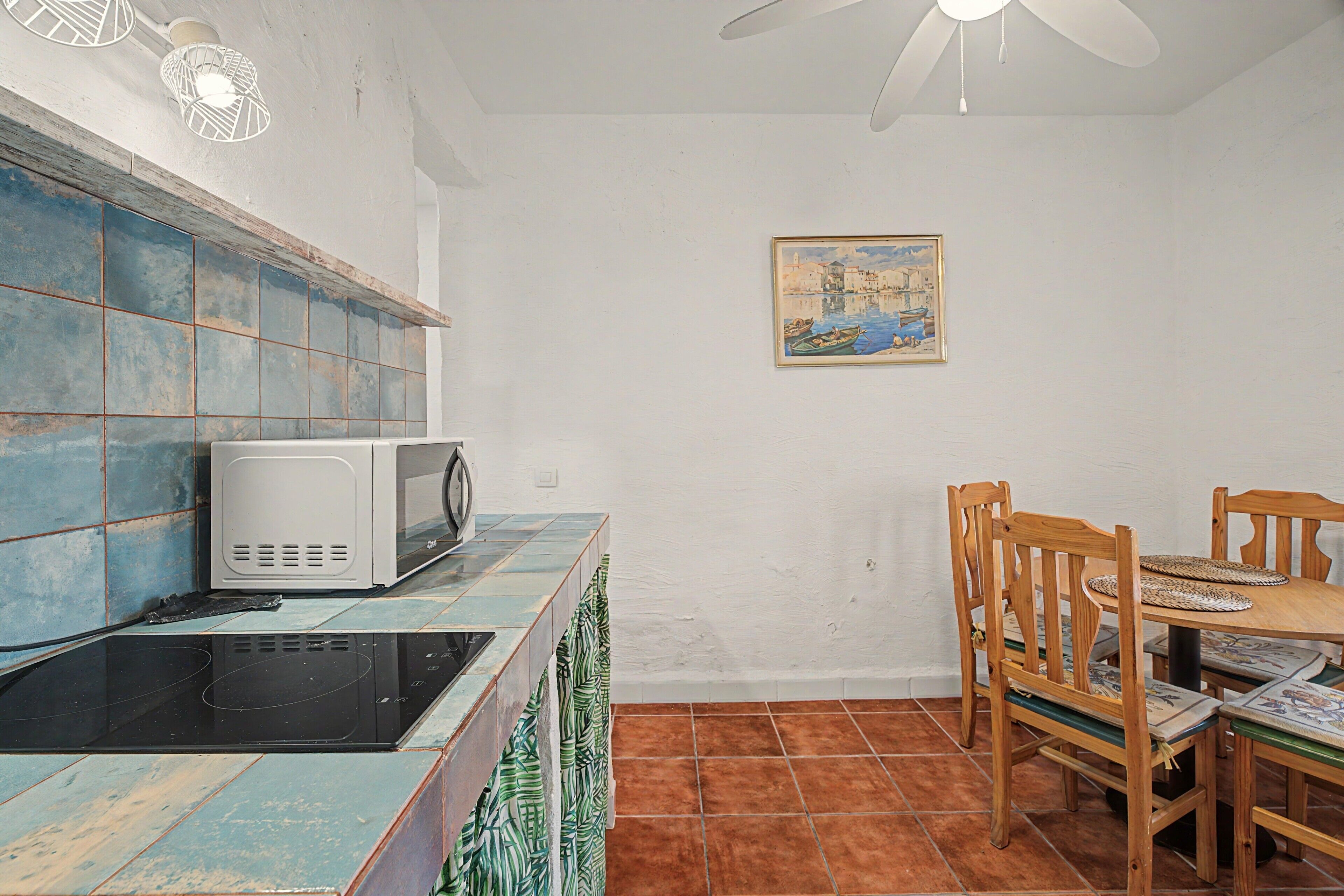 A kitchen with a microwave, a stove, and a dining table with chairs.