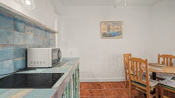 A kitchen with a microwave, a stove, and a dining table with chairs.