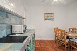 A kitchen with a microwave, a stove, and a dining table with chairs.