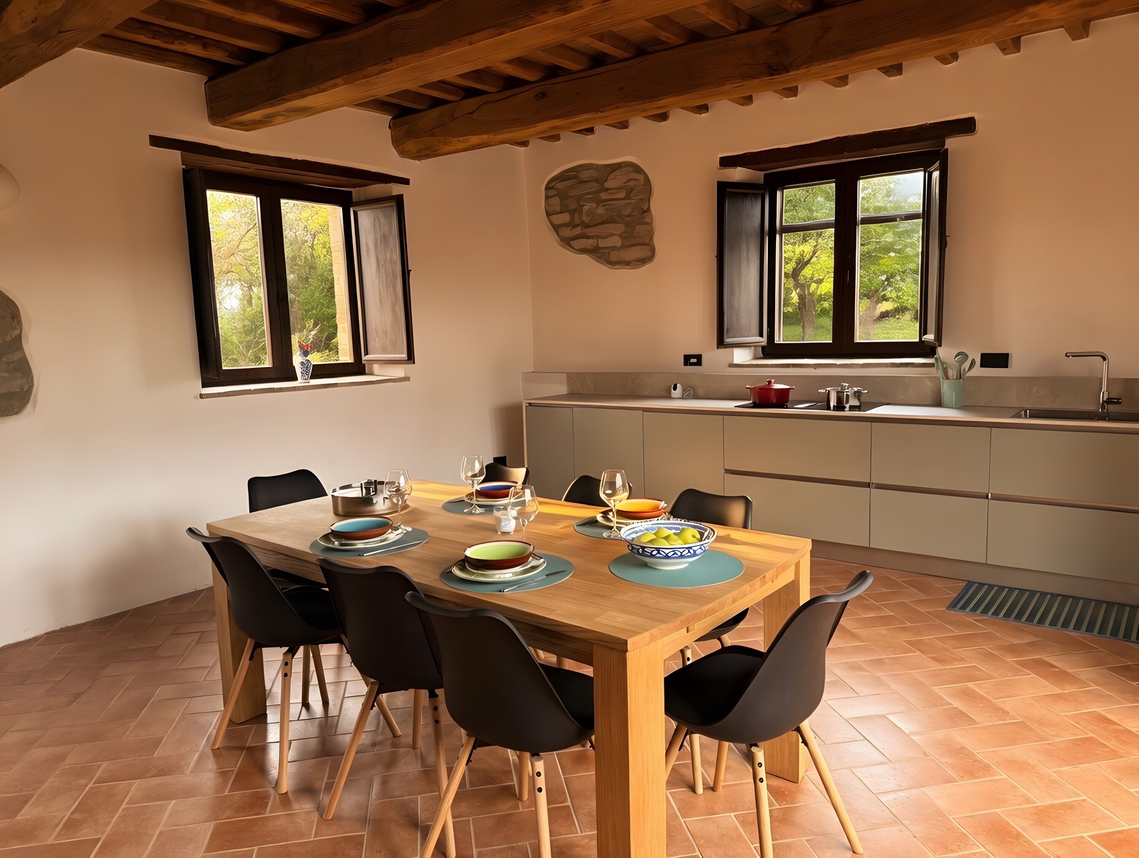 A dining area with a wooden table, black chairs, and a kitchen in the background.