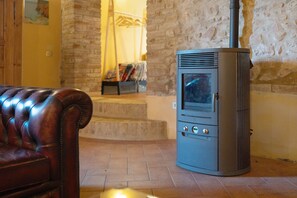 Una habitación con pared de piedra, un sofá de cuero y un estufa de leña.