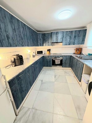 A modern kitchen with dark blue cabinets, a microwave, a toaster, and a sink. - Stunning Spacious Villa with panoramic Sea Views (Estepona)