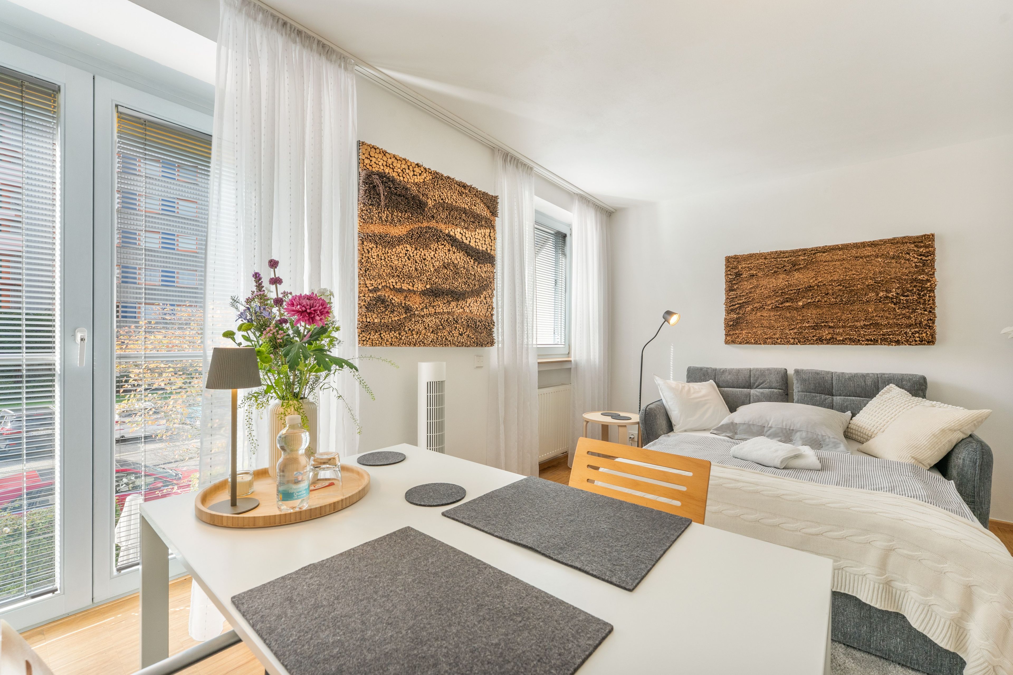 Une chambre à coucher moderne, avec un lit, une table de chevet, une lampe et des œuvres d’art accrochées aux murs.