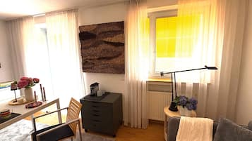 Ein gemütliches Zimmer mit Schreibtisch, Stuhl und einem fenster mit Vorhängen.