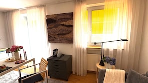 A cozy room with a desk, chair, and a window with curtains.
