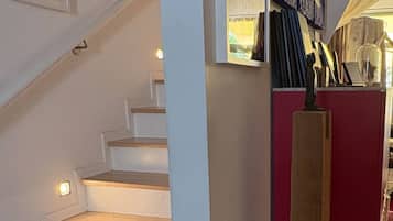 Eine Treppe mit Handlauf, die zu einer Zwischenebene mit einem roten Schrank und verschiedenen ausgestellten Gegenständen führt.