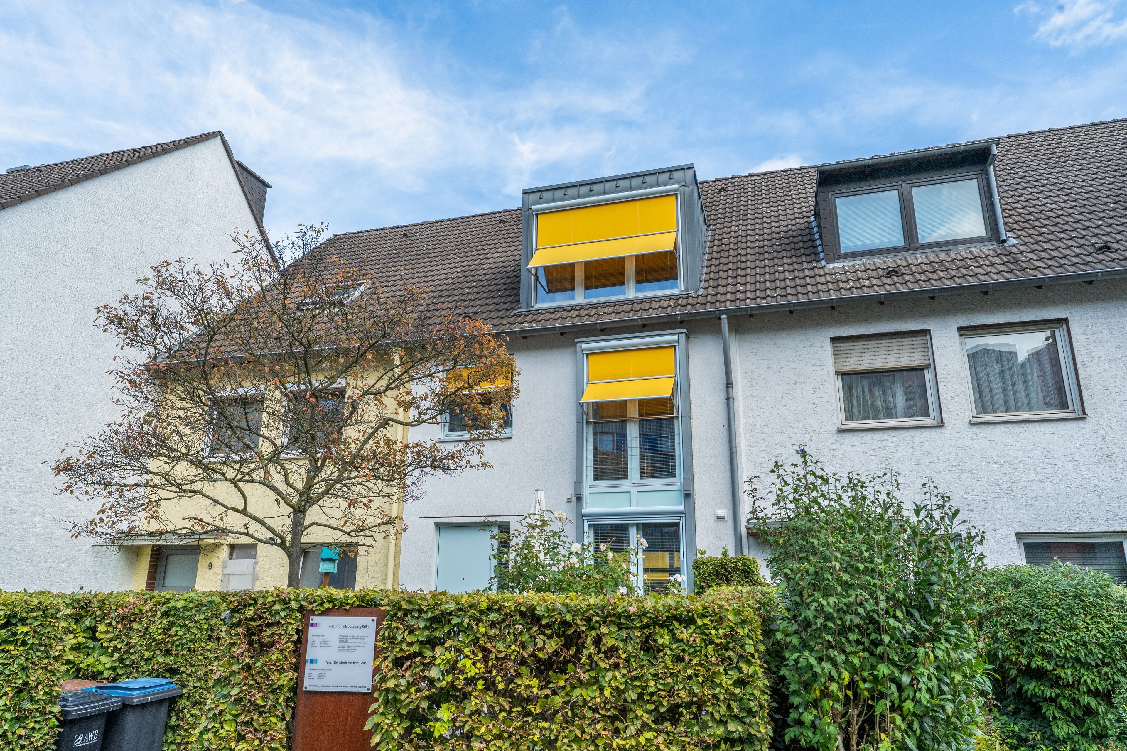 Ein Wohngebäude im modernen Stil, mit einer Mischung verschiedener Fensterformen und einem sichtbaren Gartenbereich.