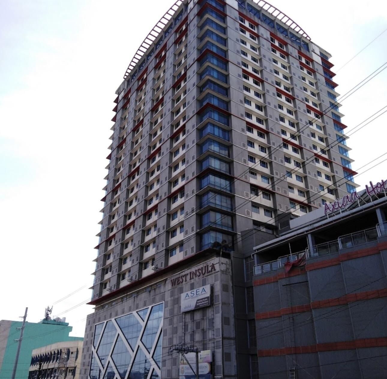 A high-rise building with multiple floors, a commercial sign at the base, and a construction site to the right.
