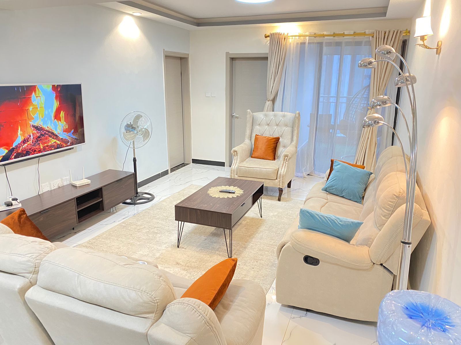 Una sala de estar moderna con un televisor de pantalla plana, un sofá, una silla y una mesa de centro.