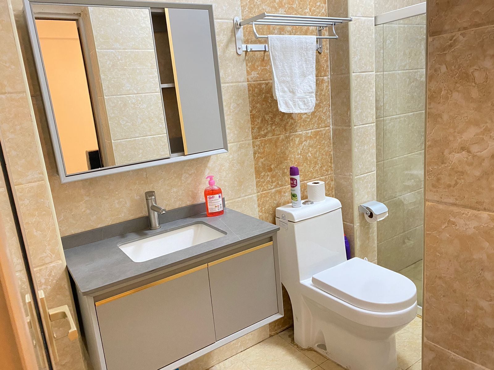 Un baño con lavamanos, inodoro y espejo.