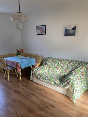 A dining area with a table and chairs, a sofa, and two framed pictures on the wall. - CASA ZANONI (Nago-Torbole)