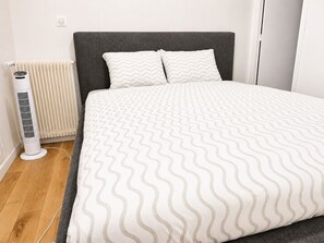 Een slaapkamer met een bed, een radiator en een elektrische kachel.
