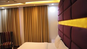 Una habitación de hotel con una cama grande, una silla y cortinas.