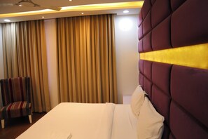 Una habitación de hotel con una cama grande, una silla y cortinas.