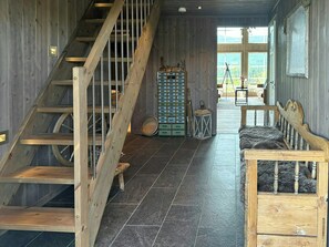A wooden interior with a staircase, a storage unit, a sofa, and a view through a window. - Cabin near Høgevarde with views and biking (Flå)