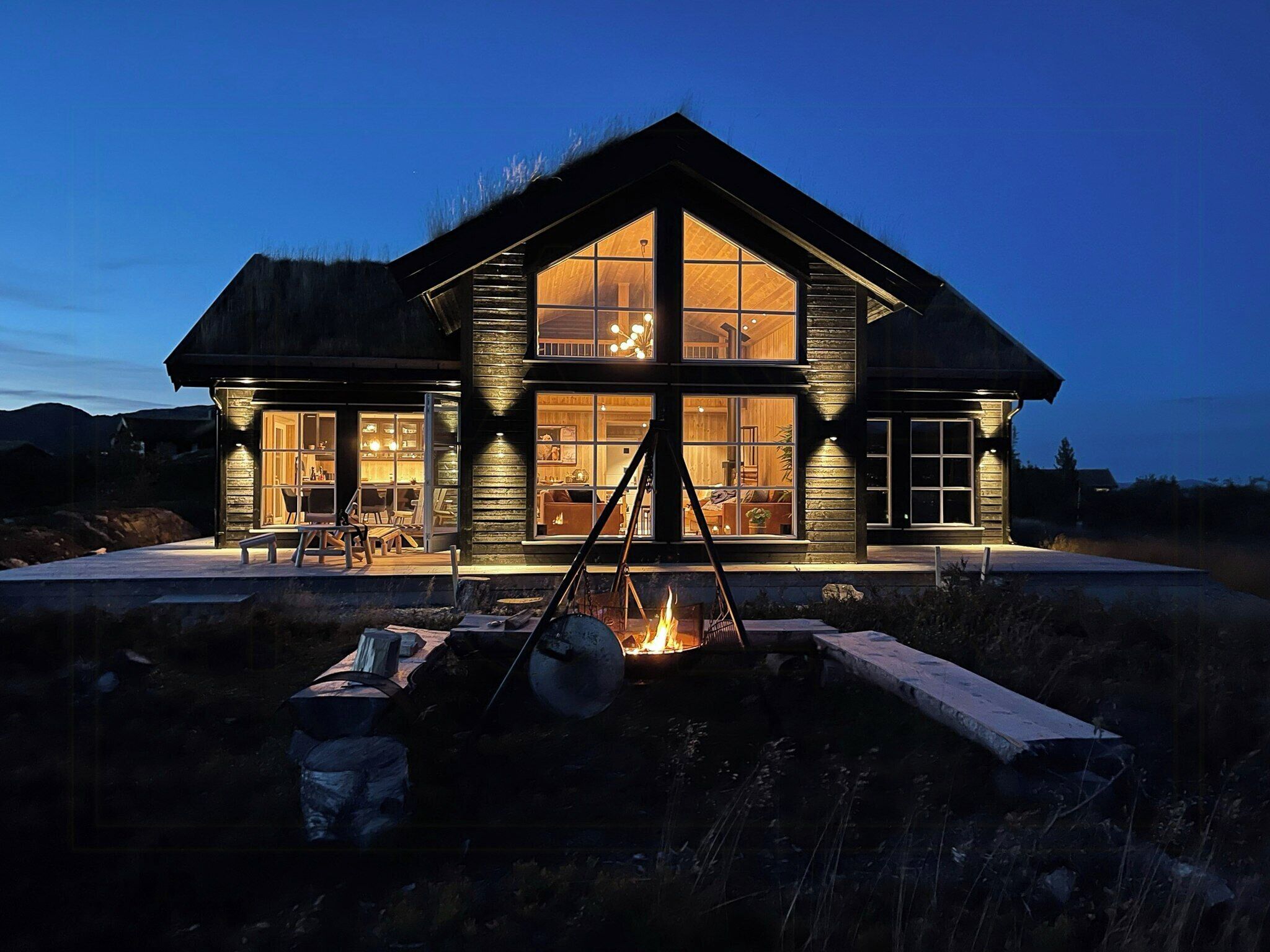 A large wooden house with a fireplace, large windows, and a deck area.