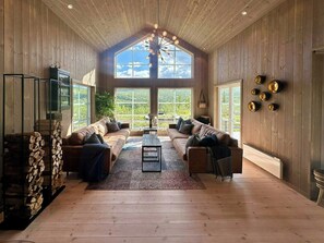 A spacious living room with a high ceiling, large windows, and a central coffee table. - Cabin near Høgevarde with views and biking (Flå)