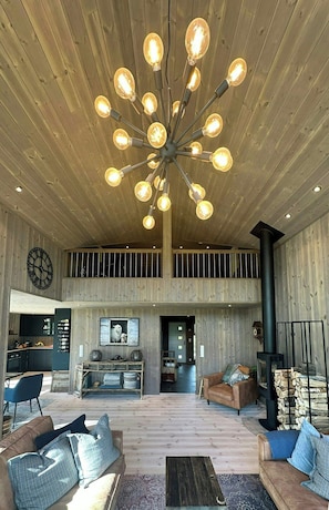 A spacious living area with a wooden ceiling, a large chandelier, and a fireplace. - Cabin near Høgevarde with views and biking (Flå)