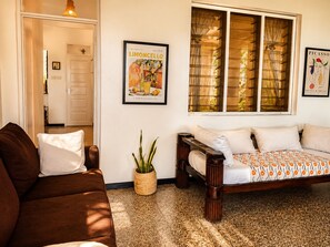 A room with a brown sofa, a bed with patterned bedding, a potted plant, and two framed pictures on the wall. - Oceanfront Hideaway Pool Beach a Coastal Escape (Malindi)