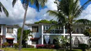 A swimming pool with a white deck, surrounded by palm trees and a two-story building with balconies. - Oceanfront Hideaway Pool Beach a Coastal Escape (Malindi)