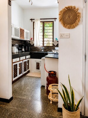 A kitchen with a gas stove, a coffee maker, and a potted plant. - Oceanfront Hideaway Pool Beach a Coastal Escape (Malindi)