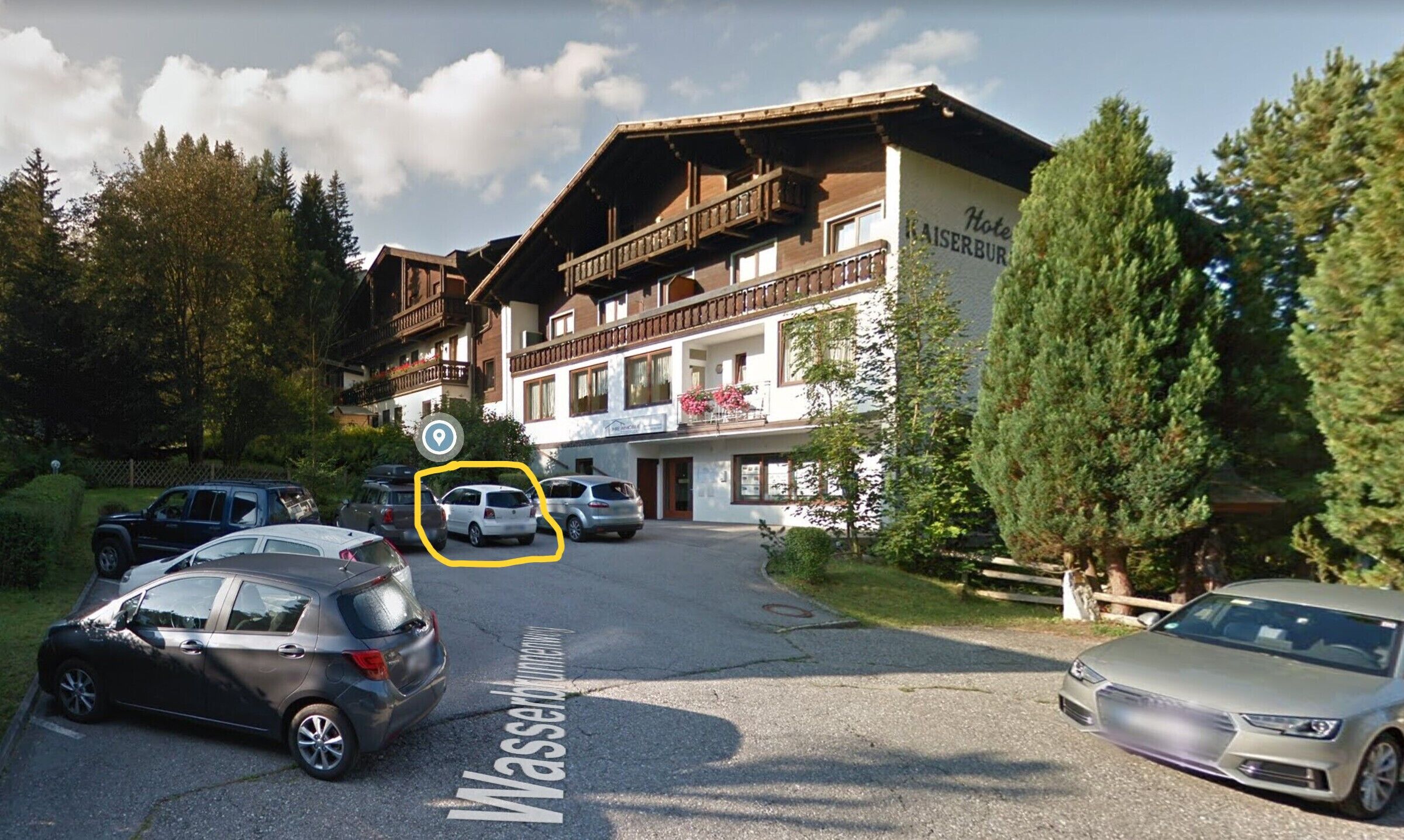 Ein Hotel im traditionellen alpinen Baustil, mit einem markanten Balkon im zweiten Stock und einem Schild mit dem Namen 'Hotel'.