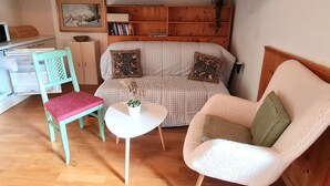 A cozy living area with a sofa, a chair, a small table, and a bookshelf. - Haus Claudia Top 9 by Globalimmoservice (Bad Kleinkirchheim)