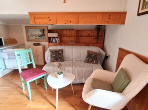 Ett mysigt vardagsrum med en soffa, en fåtölj, ett litet bord och en bokhylla.