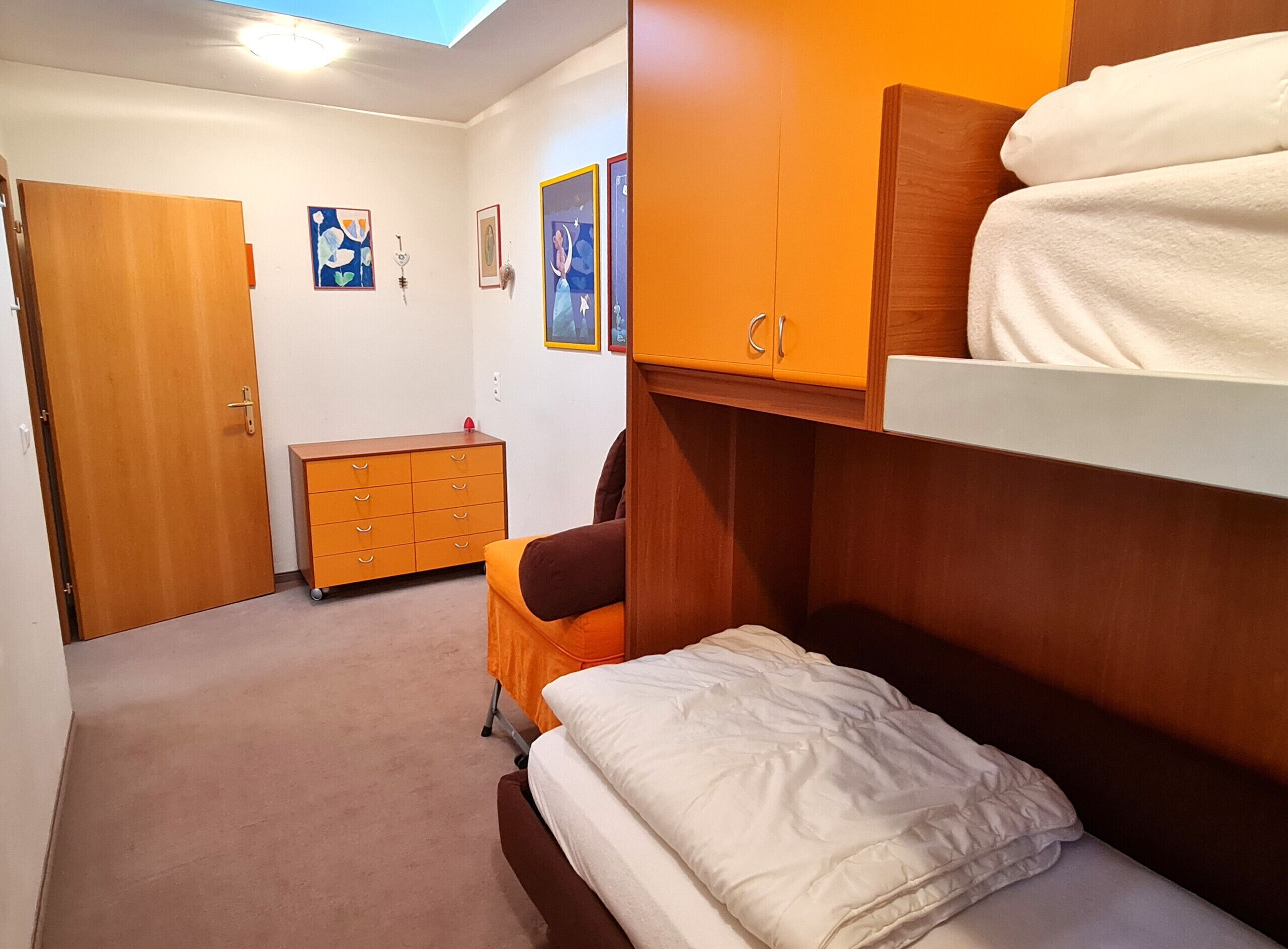 A bedroom with a bunk bed, a wooden dresser, and a small desk.