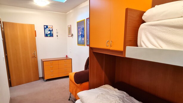 A bedroom with a bunk bed, a wooden dresser, and a small desk. - Haus Claudia Top 9 by Globalimmoservice (Bad Kleinkirchheim)