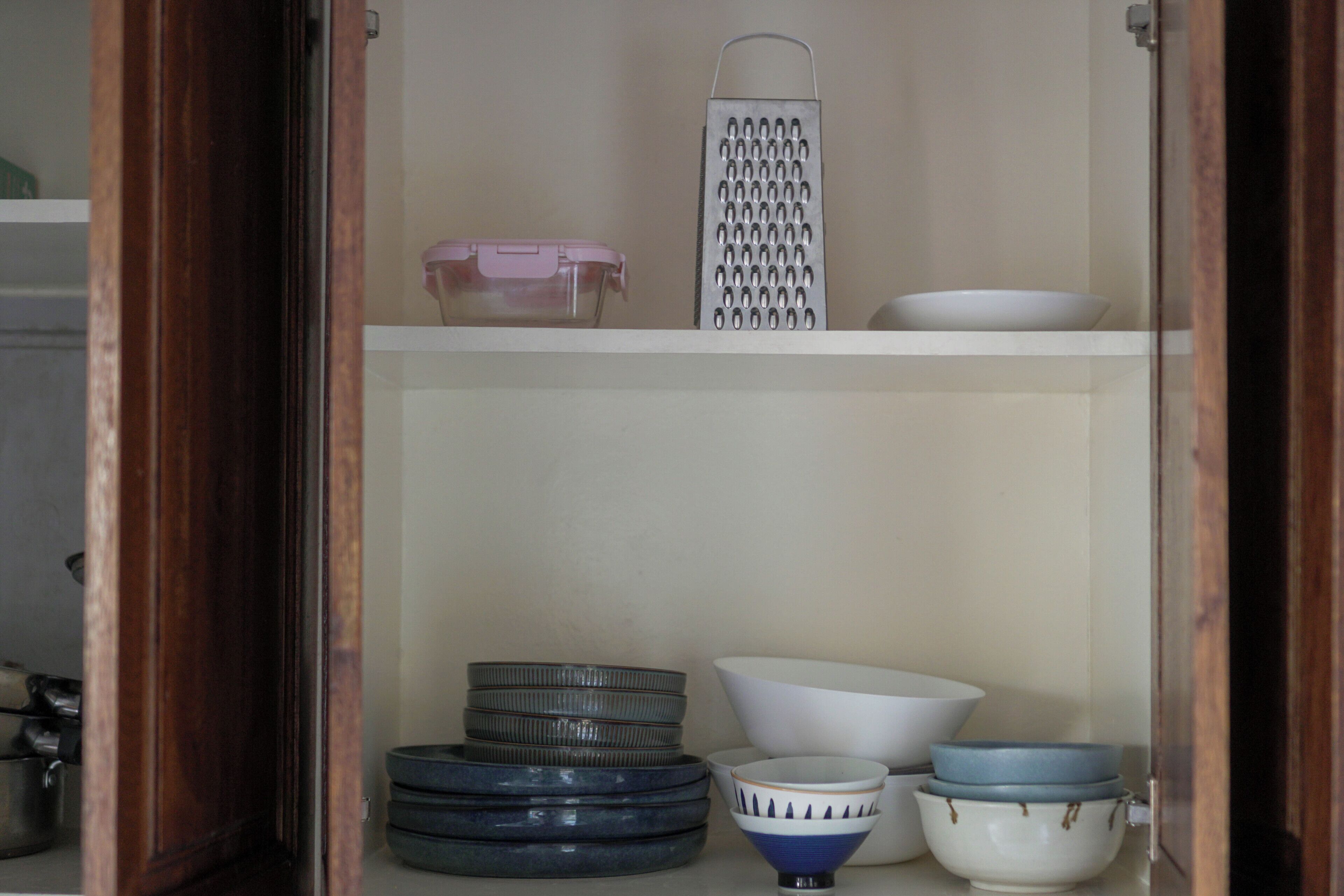 Una cocina con un rallador, tazones y platos apilados.